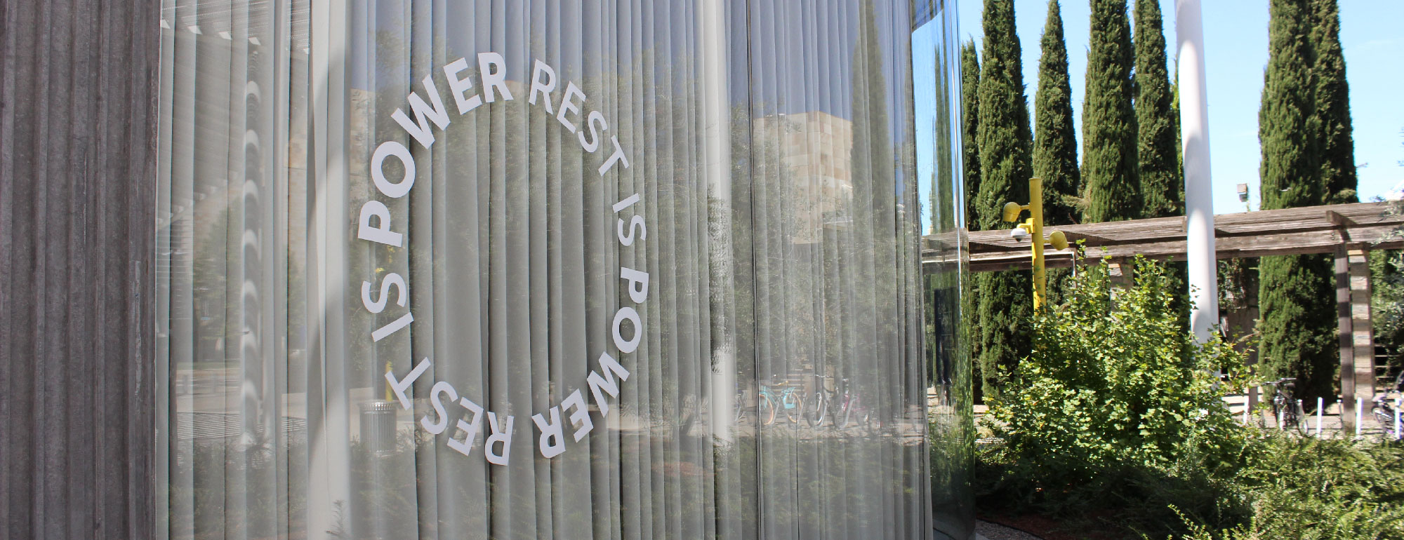 Title of exhibition reading 'Rest is Power' printed in a ring in white vinyl on the window of the museum.